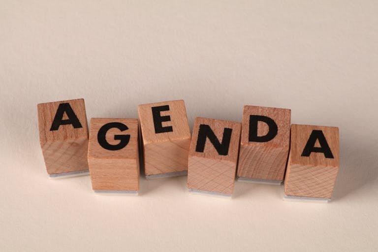 Close-up of wooden blocks spelling 'AGENDA' on a soft neutral background.